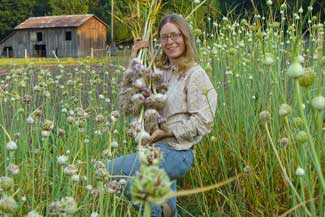 Patty holds a handful of freshly harvested hardneck garlic by Susan Fluegel at Grey Duck Garlic